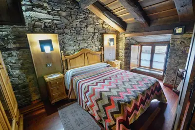 a bedroom with a bed and a stone wall at Apartamentos Casa de Riba in Teijeira