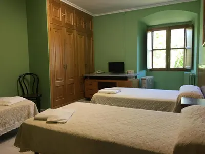 a room with two beds and a desk with a computer at San Nicolas el Real in Villafranca del Bierzo