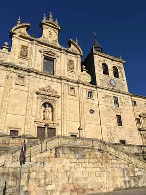 a large stone building with a clock tower at San Nicolas el Real in Villafranca del Bierzo