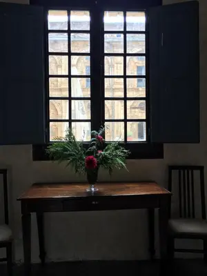 a vase of flowers on a table in front of a window at San Nicolas el Real in Villafranca del Bierzo