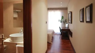 a bathroom with a sink and a bed and a mirror at Hotel Garelos Betanzos in Betanzos