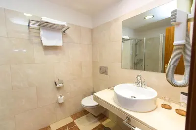 a bathroom with a sink and a toilet and a mirror at Hotel Garelos Betanzos in Betanzos