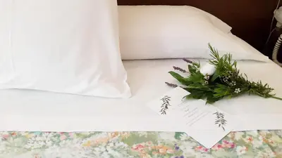 a white bed with a bouquet of flowers on it at Hotel Garelos Betanzos in Betanzos