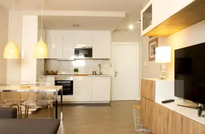 a kitchen with white cabinets and a dining room at Céntrico Burgas Termal in Ourense