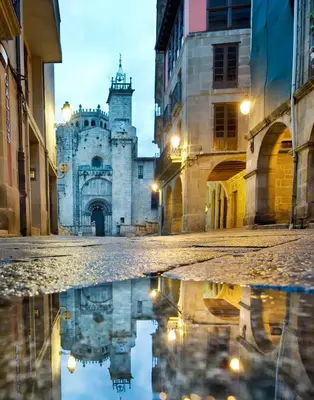 an old building with a reflection in the street at Céntrico Burgas Termal in Ourense