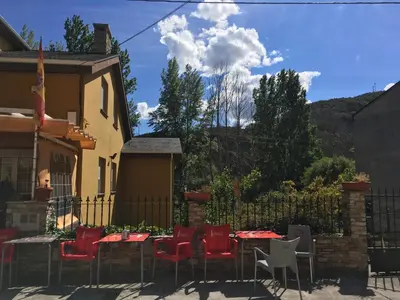 a patio with red chairs and tables in front of a house at Os Arroxos in Trabadelo