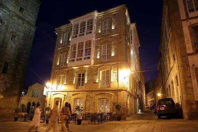 a building with people walking in front of it at night at Hotel Pazo de Altamira in Santiago de Compostela