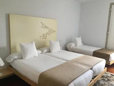 two beds in a room with white walls at Hotel Pazo de Altamira in Santiago de Compostela