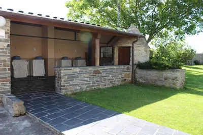 a house with a brick wall and a patio at Apartamentos Casa Cerolleiro in Castropol