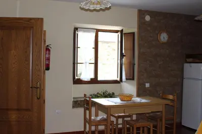 a kitchen with a table and chairs and a window at Apartamentos Casa Cerolleiro in Castropol
