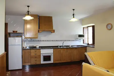 a kitchen with wooden cabinets and a white refrigerator at Apartamentos Casa Cerolleiro in Castropol