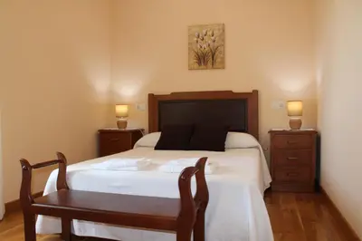 a bedroom with a bed with a table and a chair at Apartamentos Casa Cerolleiro in Castropol