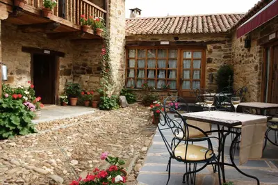 an outdoor patio with tables and chairs and flowers at Casa Pepa Hotel Rural in Santa Colomba de Somoza