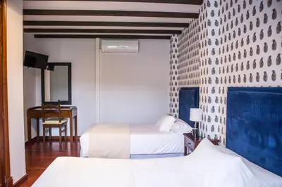 a hotel room with two beds and a desk at Hotel A Casa Do Rio in Padrón