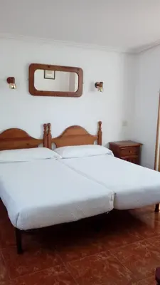 a bedroom with two white beds and a mirror at Hotel Los Perales in Puebla de Sanabria