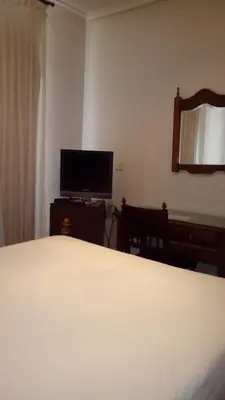 a bedroom with a bed and a flat screen tv at Hotel Los Perales in Puebla de Sanabria