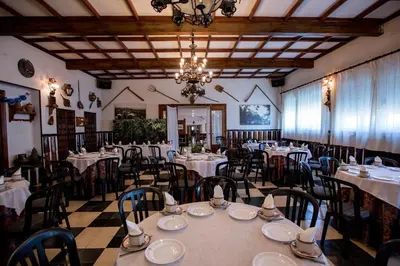 a dining room with tables and chairs and a chandelier at Hotel Los Perales in Puebla de Sanabria