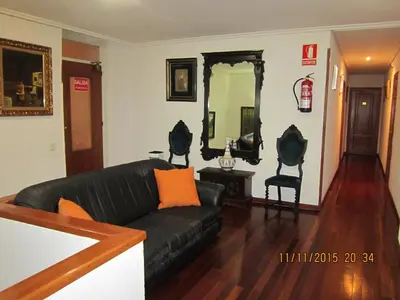a living room with a black couch and a mirror at Hotel Los Perales in Puebla de Sanabria