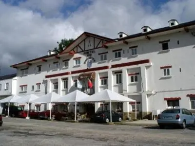 a large white building with white umbrellas in front of it at Hotel Los Perales in Puebla de Sanabria