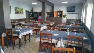 a dining room with blue tables and chairs in a restaurant at Pension Grilo in Padrón