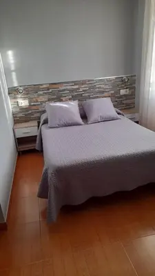 a bedroom with a bed and a brick wall at Pension Grilo in Padrón