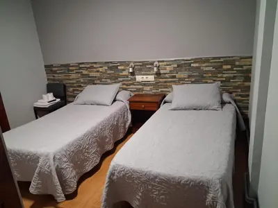 a room with two beds and a brick wall at Pension Grilo in Padrón