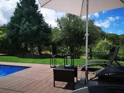 a patio with chairs and an umbrella next to a pool at San Andres Ferienhaus mit Gästehaus in Parada del Sil