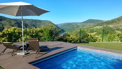 a swimming pool with two chairs and an umbrella at San Andres Ferienhaus mit Gästehaus in Parada del Sil