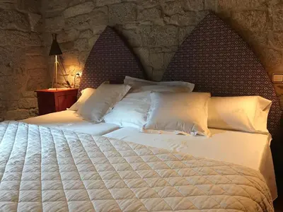 a bedroom with a large white bed with a stone wall at San Andres Ferienhaus mit Gästehaus in Parada del Sil