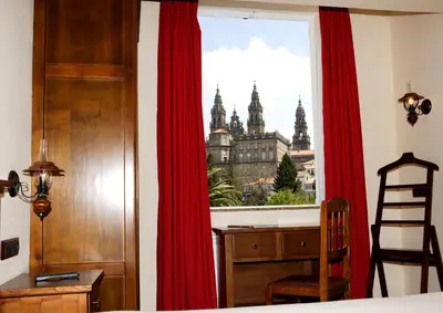 a bedroom with red curtains and a desk and a window at Hotel Pazos Alba in Santiago de Compostela
