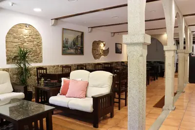a restaurant with white chairs and tables and a bar at Hotel Pazos Alba in Santiago de Compostela