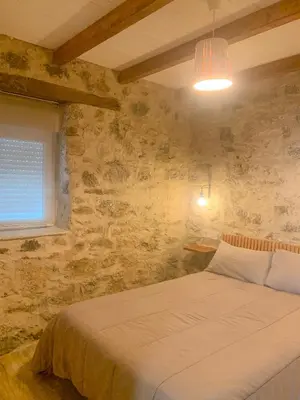 a bedroom with a bed in a stone wall at Apartamento Las Medulas in Covas