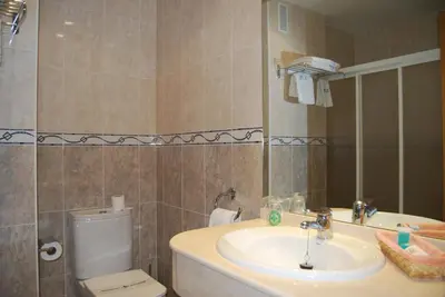 a bathroom with a sink and a toilet and a mirror at Hotel Meleiros in Castro de Sanabria