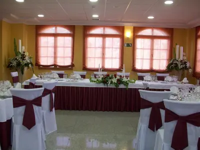 a banquet hall with white tables and chairs with bows at Hotel Meleiros in Castro de Sanabria