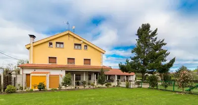 a yellow house with a tree in a yard at Hotel Casa Reboiro in Monforte de Lemos
