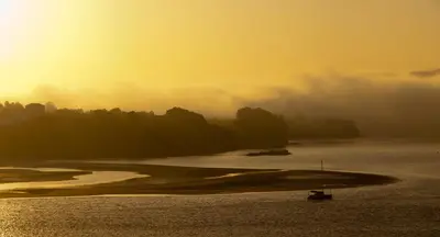 a boat in a body of water at sunset at Mirador Ría de Ribadeo in Ribadeo