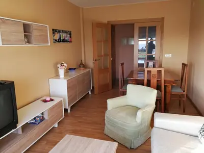 a living room with a tv and a chair and a table at Apartamento en playa de Foz in Foz