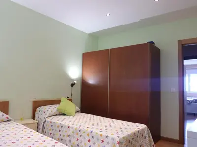 a small bedroom with two beds and a cabinet at Apartamento en playa de Foz in Foz