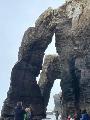 a group of people standing in front of an arch in the ocean at Apartamento en playa de Foz in Foz