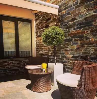 a patio with wicker chairs and a table and a brick wall at Casa do Maestro in Portomarin
