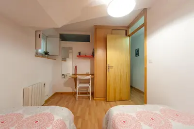 a room with two beds and a table and a door at Entrepexigos in Santiago de Compostela
