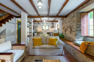 a living room with a white couch and yellow pillows at Casas del Molino - Muiños do Mainzoso Turismo Rural in Paderne