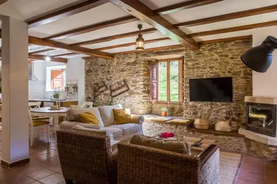 a living room with a stone wall at Casas del Molino - Muiños do Mainzoso Turismo Rural in Paderne