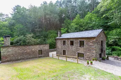 a stone house with a yard in front of it at Casas del Molino - Muiños do Mainzoso Turismo Rural in Paderne