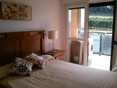 a bedroom with a bed and a window with a balcony at Apartamento Dicar in Foz