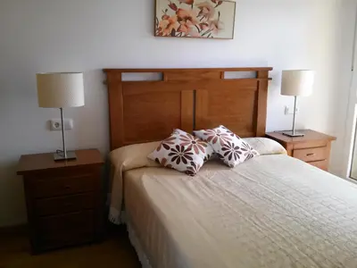 a bedroom with a bed with two night stands and two lamps at Apartamento Dicar in Foz