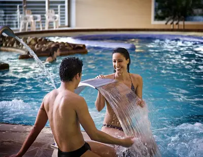 a man and a woman playing in a swimming pool at ARNOIA CALDARIA HOTEL Y BALNEARIO in Arnoia