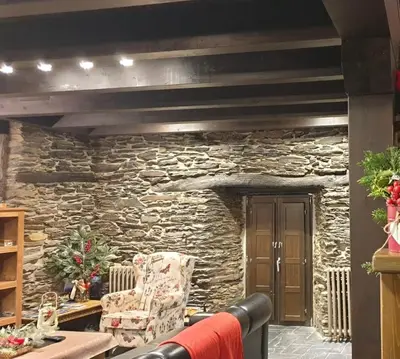 a living room with a stone wall and a chair at El Balcón de Sotillo - Las Médulas - Senderismo por Canales Romanos in Sotillo de Cabrera