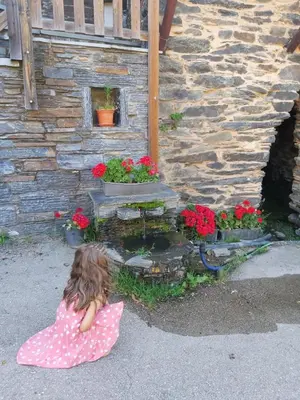 a little girl sitting on the ground in front of a fountain at El Balcón de Sotillo - Las Médulas - Senderismo por Canales Romanos in Sotillo de Cabrera