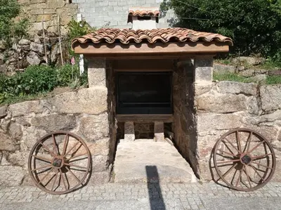 a stone building with two largeoked wheels in front at Apartamento Carballo Do Xurès in Maus de Salas